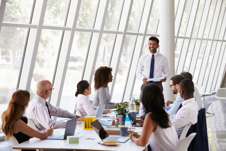 Hispanic Businessman Leading Meeting At Boardroom Table